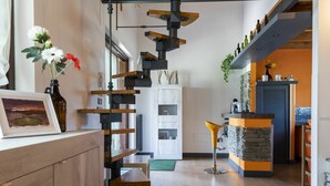 A modern kitchen with a wooden staircase, a dining area, and a stone accent wall. - Wonderful private villa for 5 people with A/C, private pool, WIFI, TV, terrace and panoramic view (Sutri)