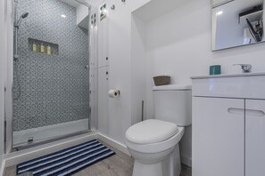 Un baño moderno con ducha, inodoro y tocador.