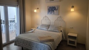 Een slaapkamer met een bed, nachtkastje, airconditioning, wandlamp en raam met uitzicht.