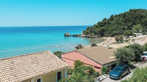 A coastal view with a clear sky, a beach, and buildings with tiled roofs.
