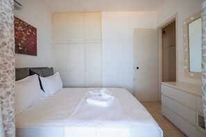 A hotel room with a bed, a wardrobe, a dresser, and a painting on the wall. - Corfu Glyfada Menigos Resort 91 (Corfu)