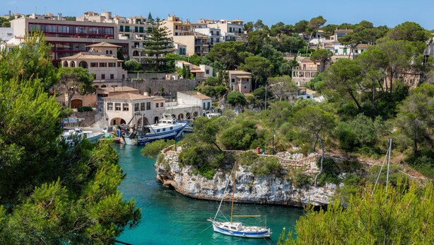 Un pueblo costero con edificios, un puerto deportivo y barcos.
