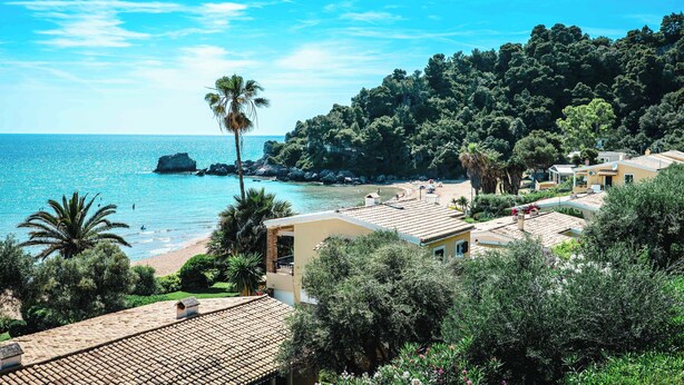 A coastal villa with a view of the sea, surrounded by lush greenery and a rocky outcrop. - Corfu Glyfada Menigos Resort 46 (Corfu)