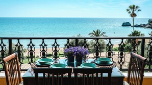 A balcony with a table set for two, overlooking a beach and the ocean. - Corfu Glyfada Menigos Resort 46 (Corfu)