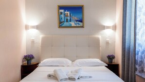 A hotel room with a bed, pillows, a painting, bedside tables with flowers, and a curtain. - Corfu Glyfada Menigos Resort 46 (Corfu)