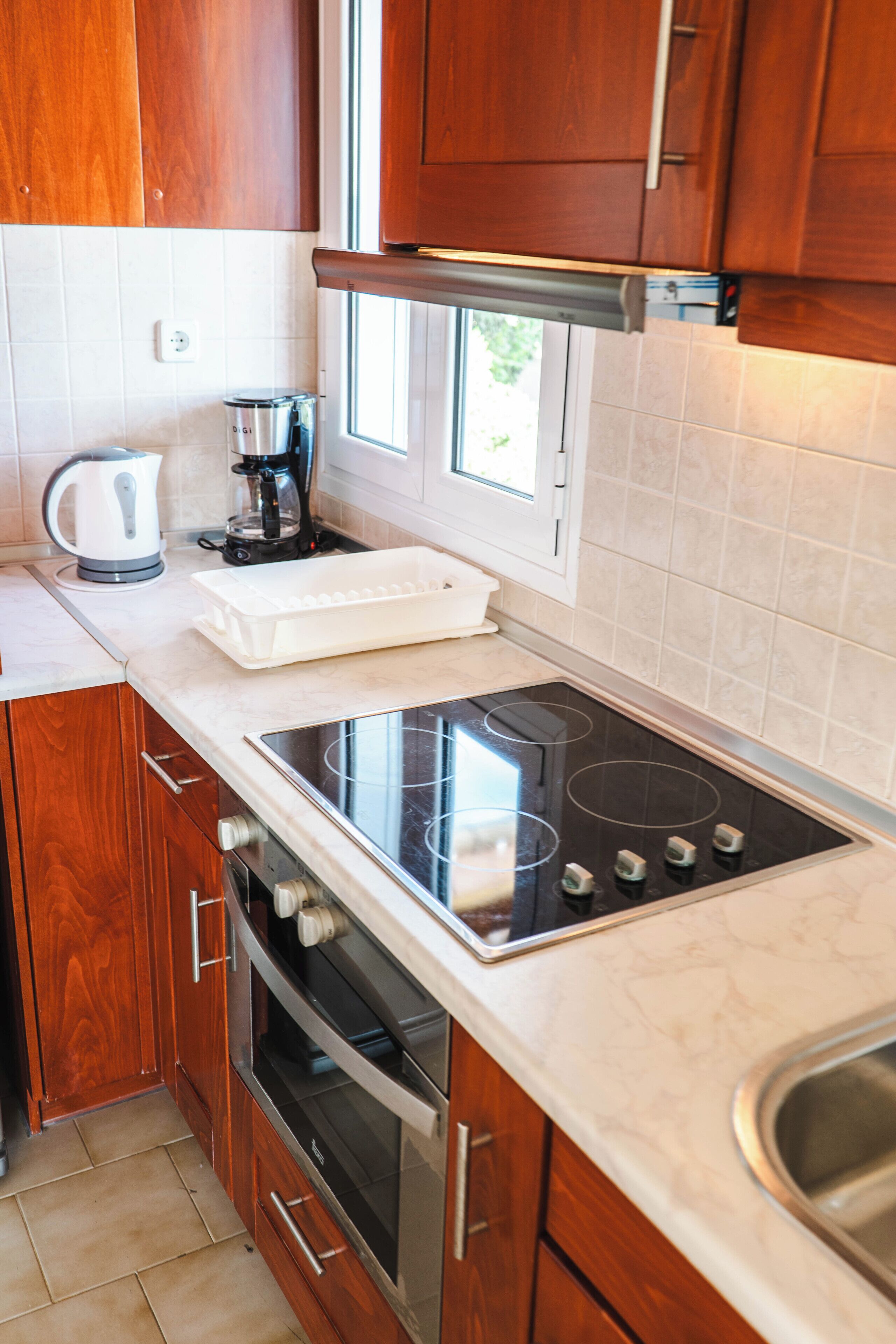 Una cocina con armarios de madera, horno empotrado, placa de cocina y ventana.