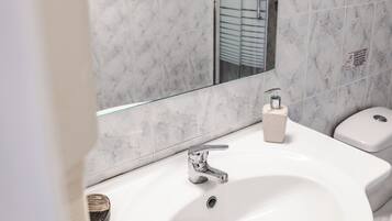 Un baño con lavamanos blanco, espejo e inodoro.