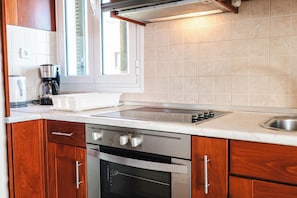 A kitchen with wooden cabinets, a built-in oven, a stovetop, and a window.