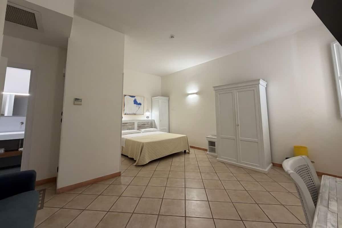 Un dormitorio con cama, armario y baño con espejo y lavamanos.