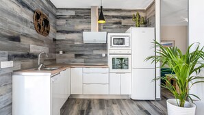 Een moderne keuken met witte kastjes, een ingebouwde magnetron en een houten aanrecht.