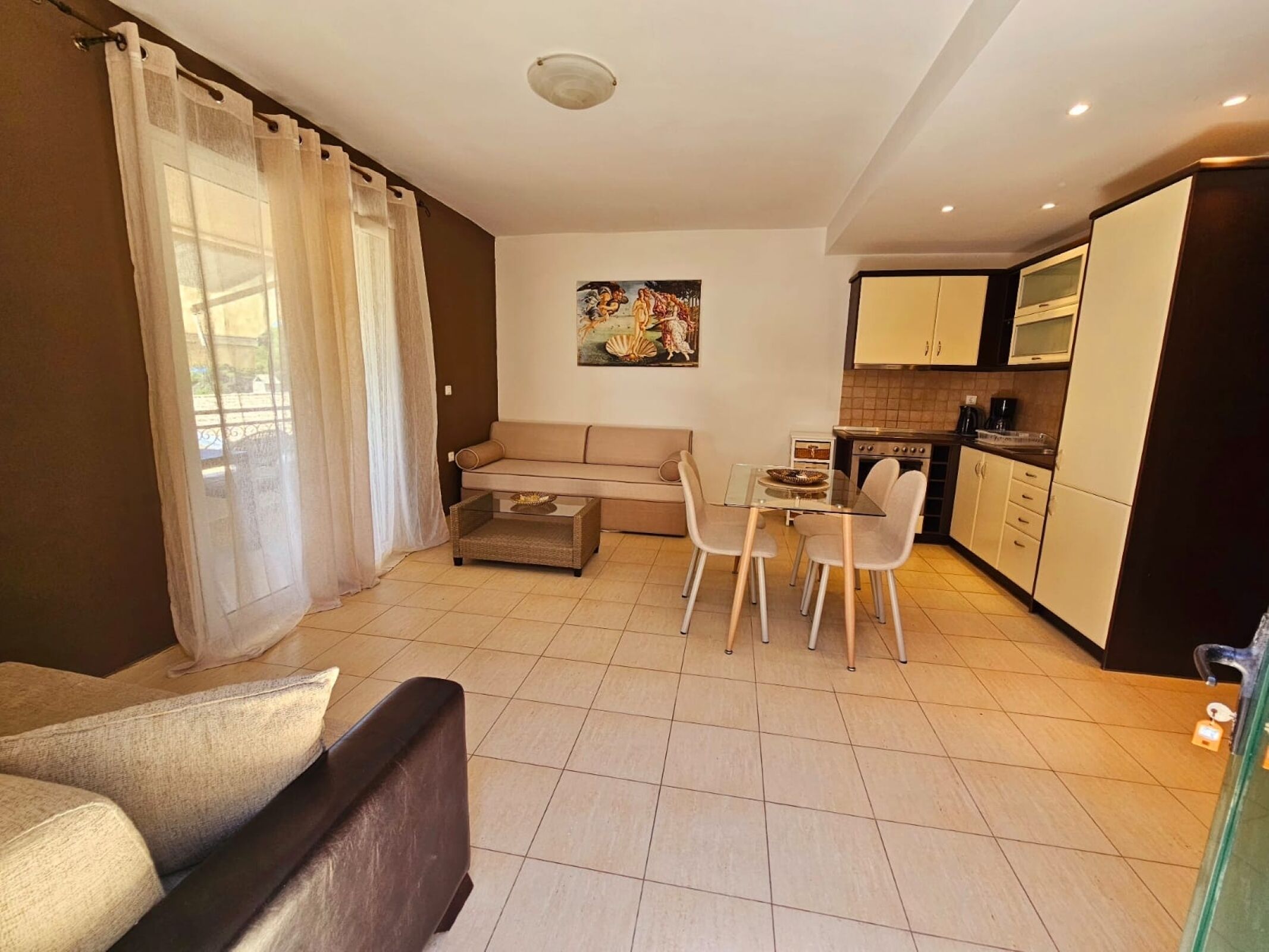 A compact living space with a sofa, dining table, chairs, and a kitchenette.
