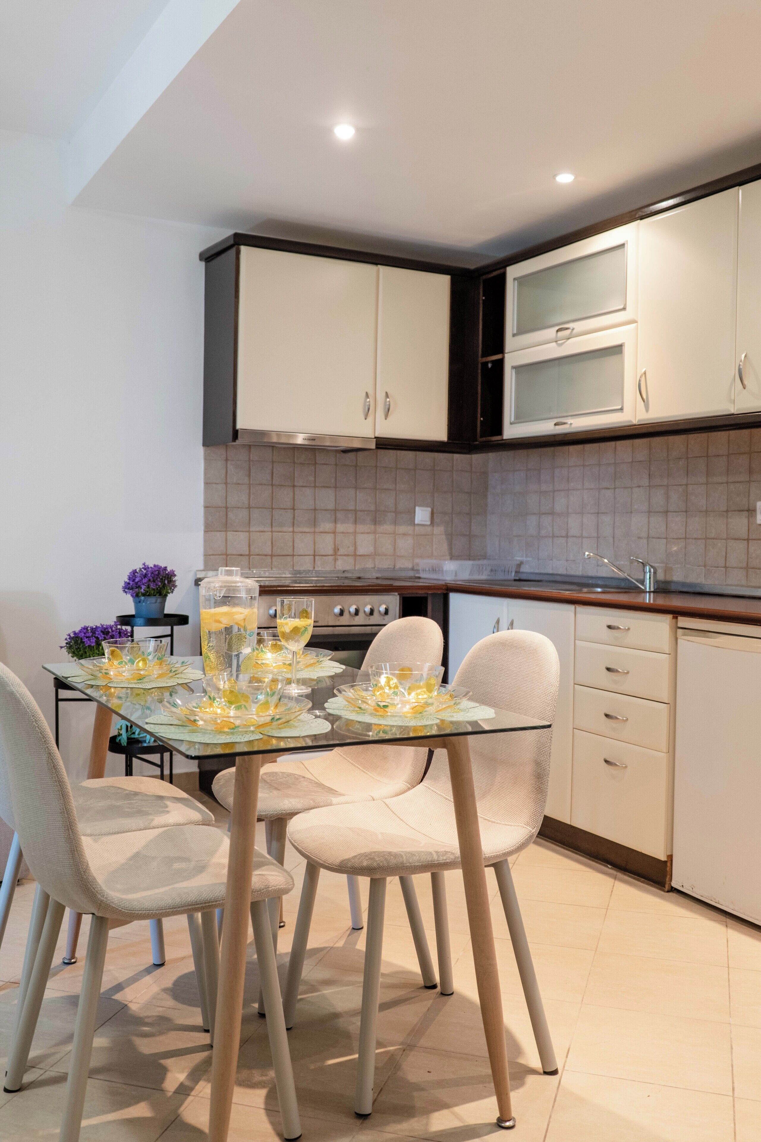Une cuisine moderne avec des meubles blancs, une table à manger avec des chaises et un îlot de cuisine.