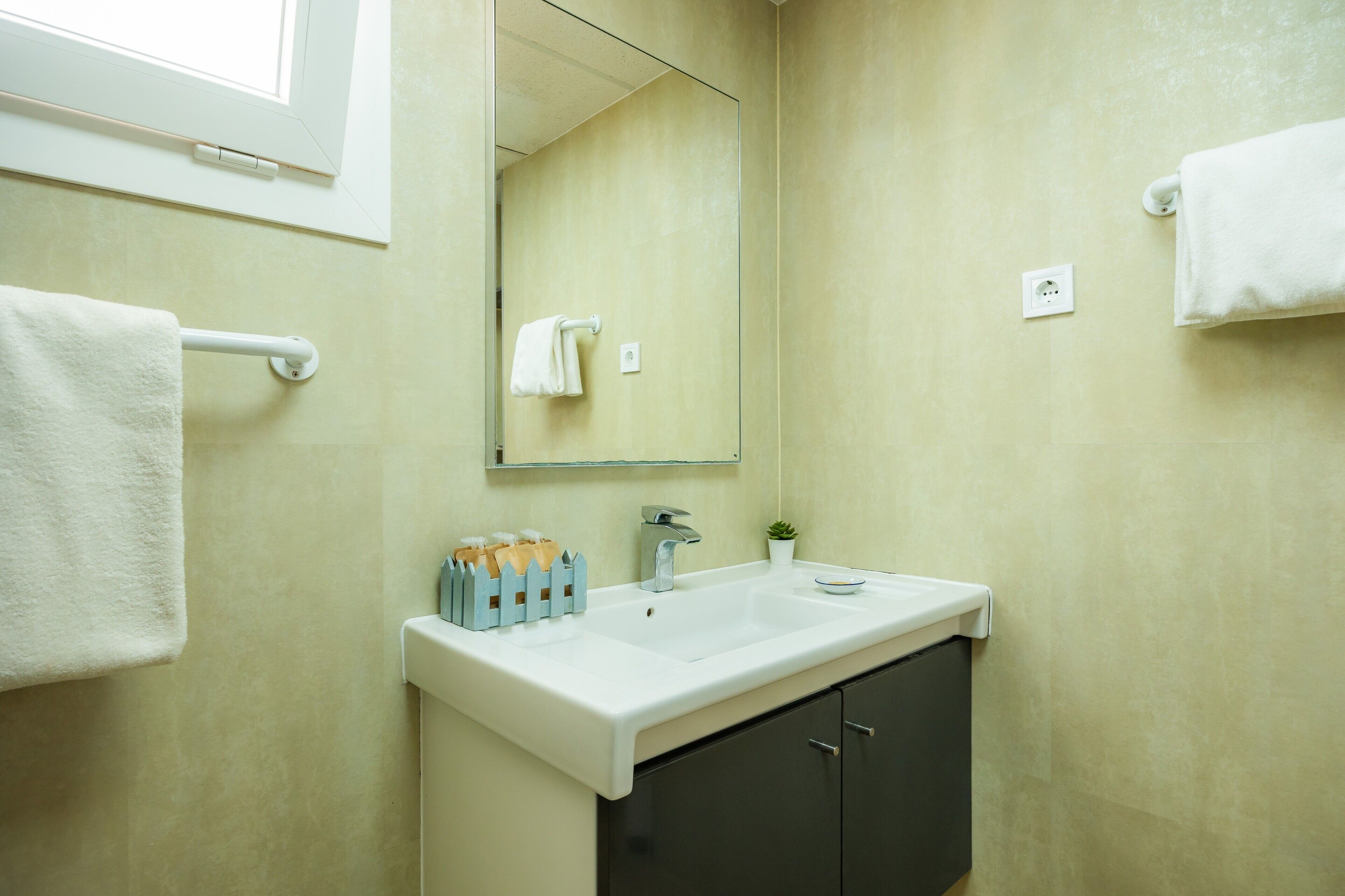 A bathroom with a white sink, dark cabinets, a mirror, and a towel rack.
