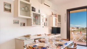A dining area with a table set for four, a television, and a view of the outdoors.