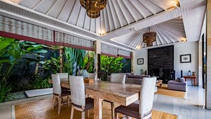 A spacious living area with a wooden dining table, wicker chairs, a sofa, and a fireplace.