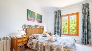 Ein Schlafzimmer mit Bett, Nachttisch, Lampe und einem Bild an der Wand.