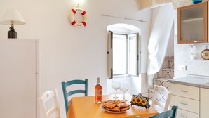 A dining area with a table set for two, a life preserver on the wall, and a view of the outside. - Vico Delle Palme (Monopoli)