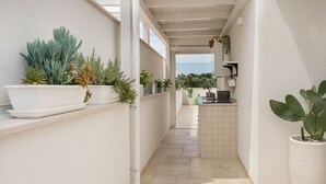 A narrow corridor with potted plants on shelves and a tiled floor. - Suite Martino Seaview (Monopoli)