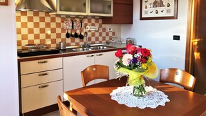 A kitchen with white cabinets, a checkered backsplash, and a dining table with a vase of flowers. - Stella del Mare (Monopoli)
