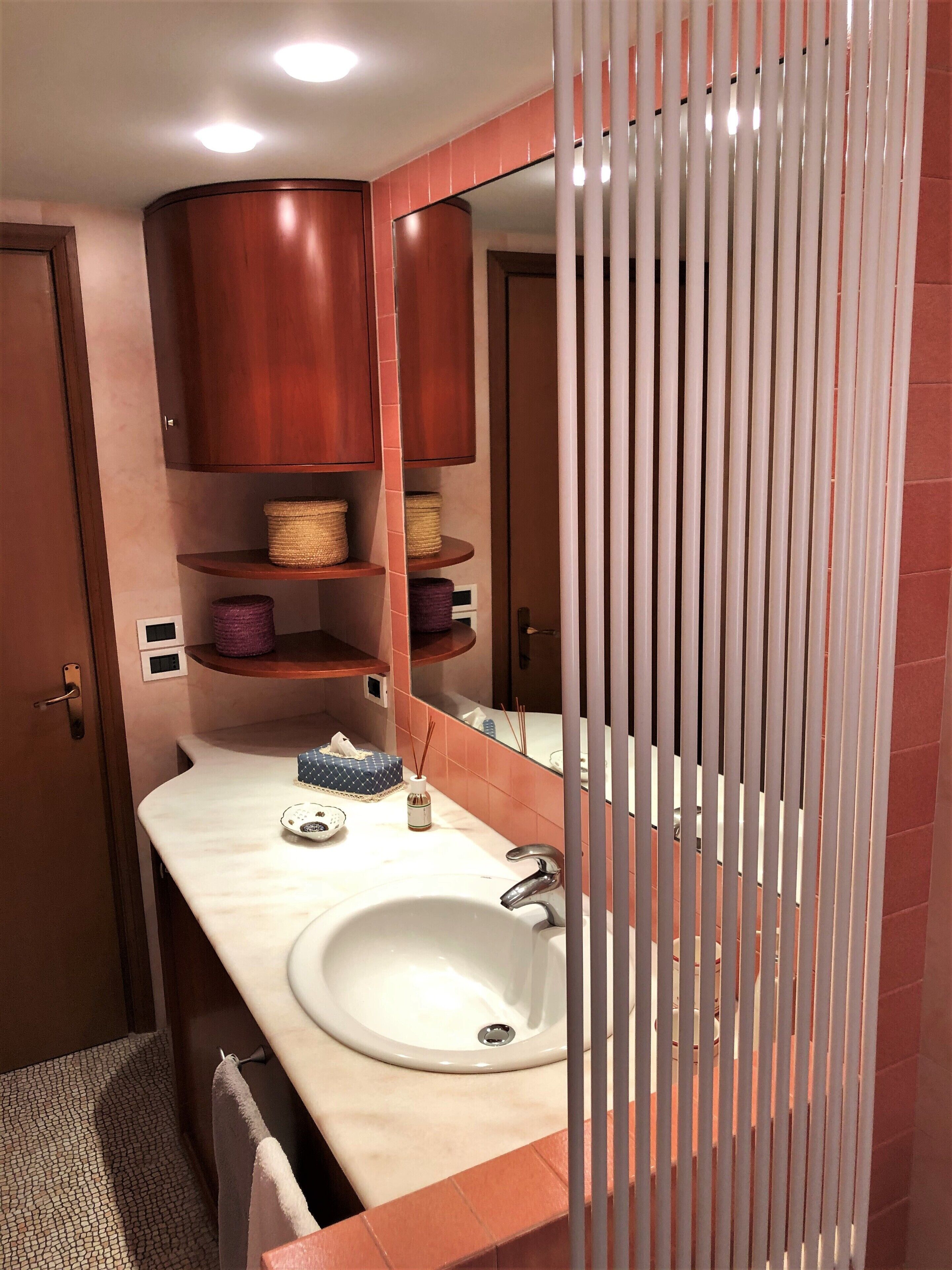 A bathroom with a white sink, wooden cabinets, and a mirror.