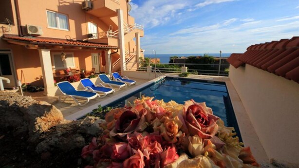 Un espace aménagé au bord de la piscine, avec des chaises longues et une vue sur la mer.