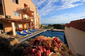 Ein Poolbereich mit Liegestühlen und Blick aufs Meer.