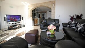 Un salon moderne avec un téléviseur à écran plat, des canapés en cuir, une table basse et un vase décoratif.