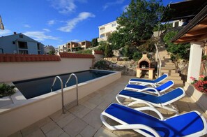A swimming pool with lounge chairs, a stone wall, and a staircase leading to a building. - Apartman Ana Cavtat (Konavle)