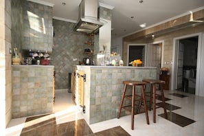 Kitchen features a central island with stools, range hood, oven, and various appliances.