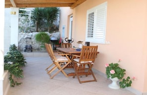 Enjoy dining or socializing in this patio area with a table and chairs, shaded by a pergola.