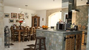 Une cuisine avec un mur recouvert de carreaux, des meubles en bois, un coin bar et un ensemble de table et chaises.