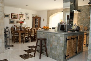 Enjoy cooking and dining in this well-appointed kitchen with a central island, stove, and microwave, complemented by a dining area with a wooden table and chairs.
