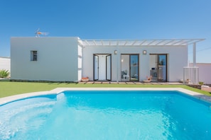 Una casa moderna con piscina, patio e cielo sereno.