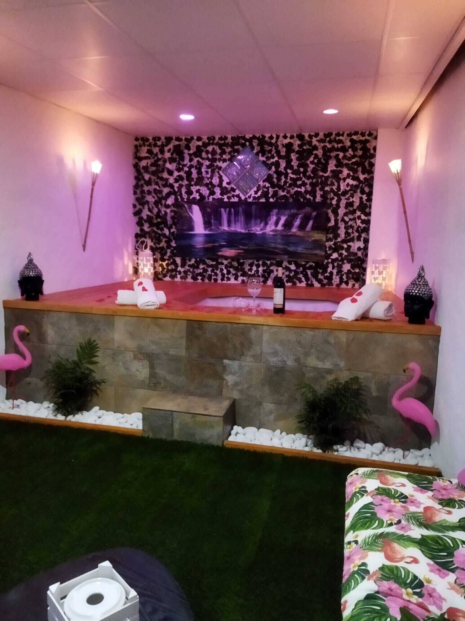 Un cuarto de spa con un banco de piedra, un cuadro de cascada en la pared y dos flamencos.