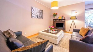 Una sala de estar con sofá, reposapiés, mesa de centro y televisor.