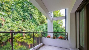 Un balcón con vistas a abundante vegetación y una ventana con cortina.