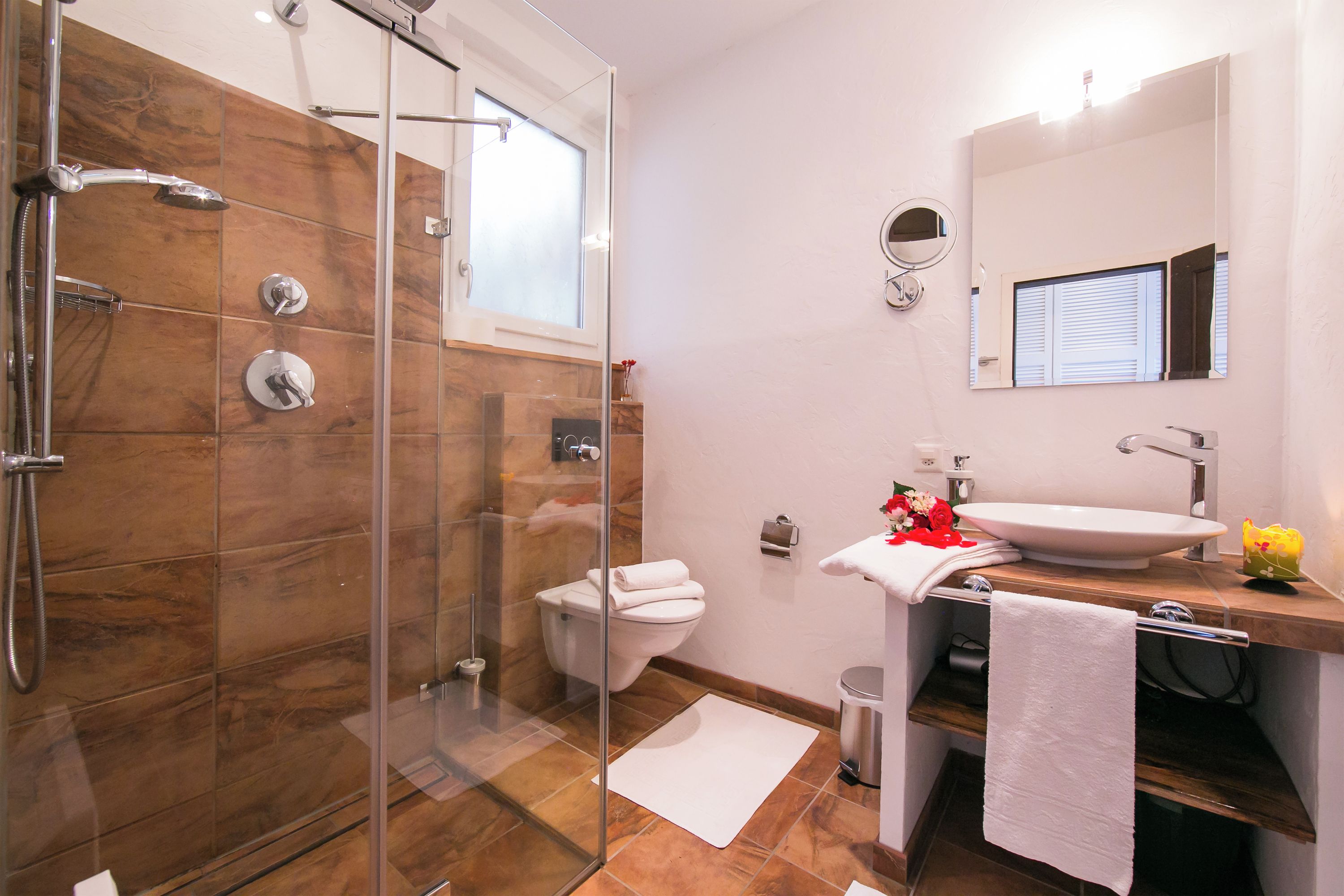 A modern bathroom with a glass-enclosed shower, a white toilet, and a sink with a mirror above it.
