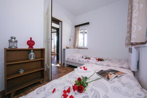 A bedroom with two beds, a wooden shelf, and a window with curtains. - Morcote Magic View (Morcote)