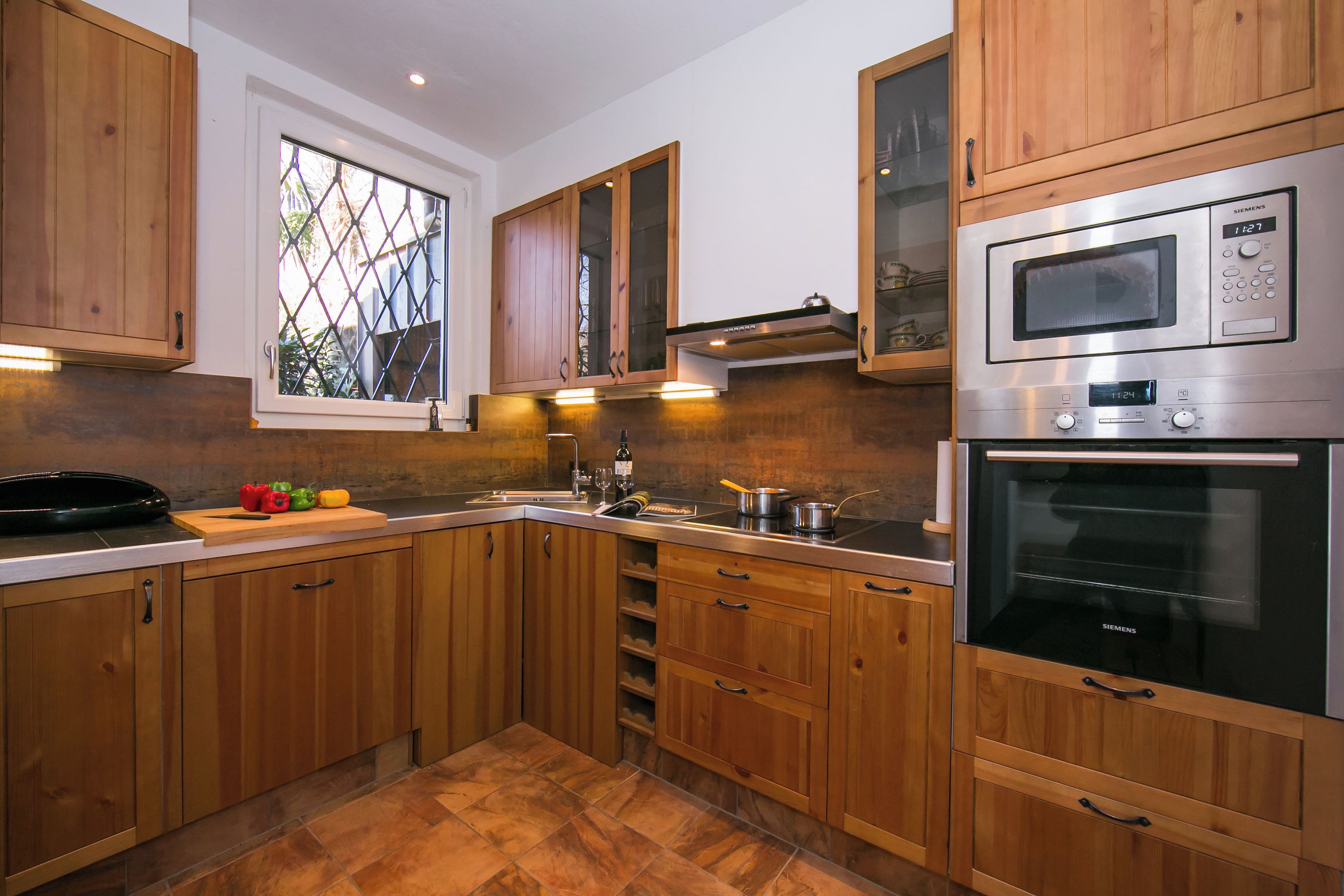 A modern kitchen with wooden cabinets, a stainless steel microwave, and an oven.