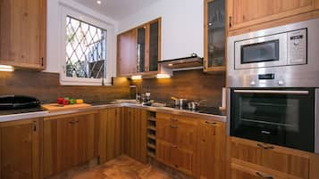 A modern kitchen with wooden cabinets, a stainless steel microwave, and an oven.