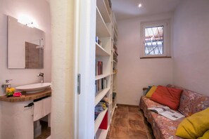 A bathroom with a sink, mirror, and shelves, a window with a view, and a sofa with cushions. - Morcote Magic View (Morcote)