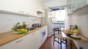 A compact kitchen with white cabinets, a wooden countertop, and a dining area with a table set for two.