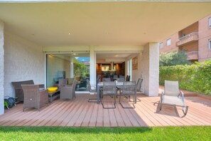 Un patio al aire libre con una mesa de comedor, sillas, un cuenco amarillo y mobiliario de mimbre.