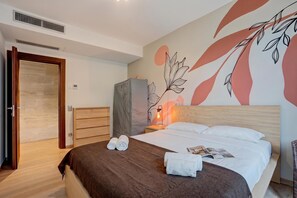 Una habitación de hotel con una cama, una mesita de noche, una lámpara, un armario y una pared con un diseño de hojas.