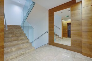 Un interior moderno con una escalera espiral, un espejo grande y paneles de madera.