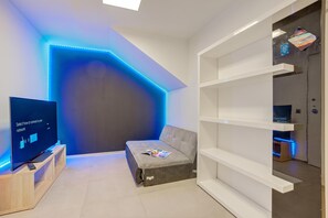 Una sala moderna con un televisor de pantalla plana, un sofá y una estantería.