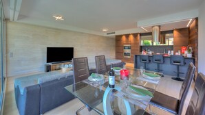 Una sala de estar moderna con una mesa de vidrio, sofás y una televisión.