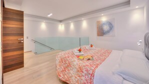 Un dormitorio moderno con cama, separador de vidrio y puerta de madera.