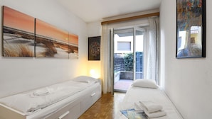 A bedroom with a bed, a bedside table, a nightstand, and a window with curtains. - Santiago Home (Lugano)
