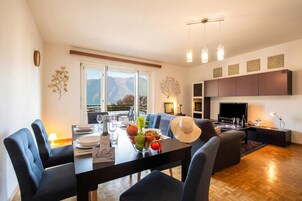 A modern living room with a dining area, a fireplace, and a view of mountains.